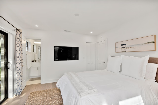 bedroom with ensuite bathroom, a closet, light hardwood / wood-style floors, and multiple windows