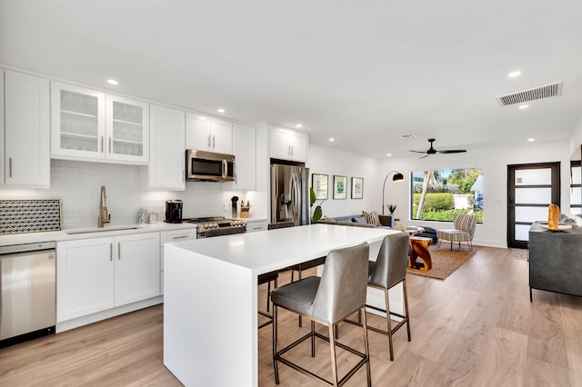 kitchen featuring a breakfast bar, white cabinets, appliances with stainless steel finishes, and sink