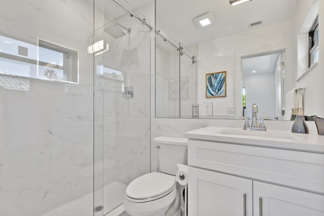 bathroom featuring a wealth of natural light, a shower with shower door, vanity, and toilet