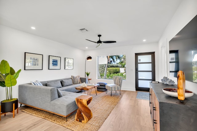 living room with light wood-type flooring, ceiling fan, and sink