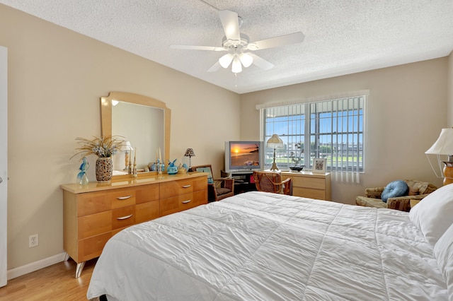 bedroom featuring ceiling fan, a textured ceiling, and light hardwood / wood-style flooring