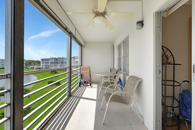 sunroom featuring a water view and ceiling fan