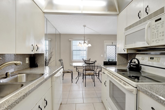 kitchen with hanging light fixtures, white appliances, white cabinetry, a notable chandelier, and decorative backsplash