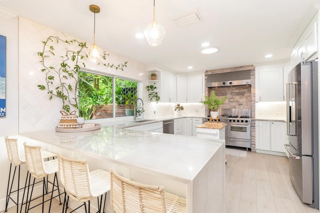 kitchen featuring high end appliances, white cabinetry, and kitchen peninsula