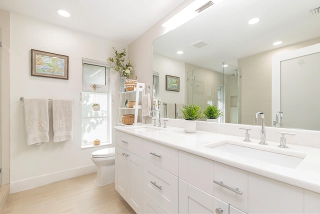 bathroom featuring a shower with shower door, toilet, and vanity