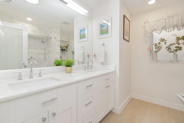 bathroom with a tile shower, wood-type flooring, and vanity