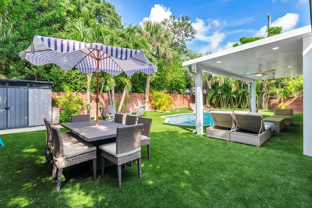 view of yard with ceiling fan, a storage shed, and a fenced in pool