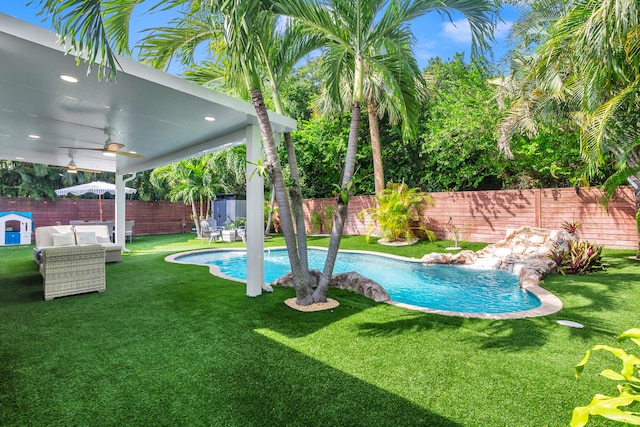 view of swimming pool featuring ceiling fan, an outdoor living space, and a lawn