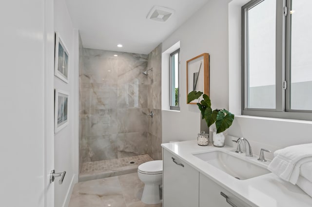 bathroom with a tile shower, vanity, and toilet