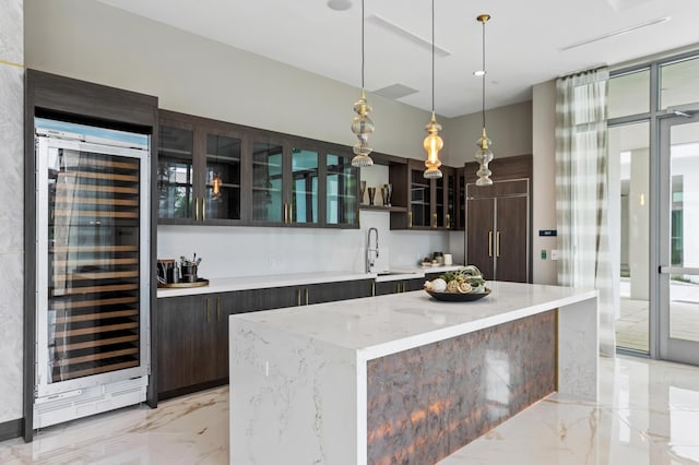 kitchen with paneled fridge, beverage cooler, a kitchen island, sink, and hanging light fixtures