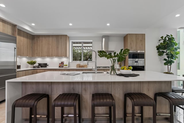 kitchen with a center island with sink, a kitchen bar, appliances with stainless steel finishes, and sink