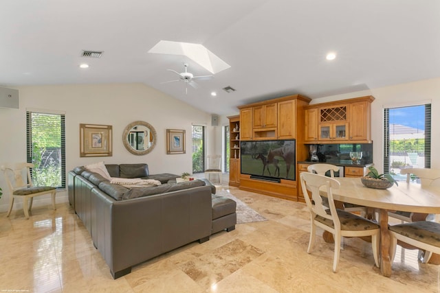 living room with ceiling fan, vaulted ceiling with skylight, and a healthy amount of sunlight