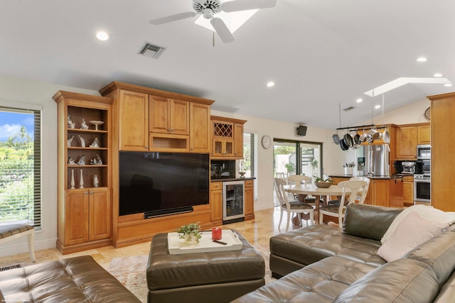 tiled living room featuring vaulted ceiling with skylight, wine cooler, and ceiling fan