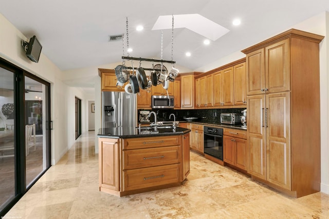 kitchen featuring an island with sink, vaulted ceiling with skylight, backsplash, and appliances with stainless steel finishes