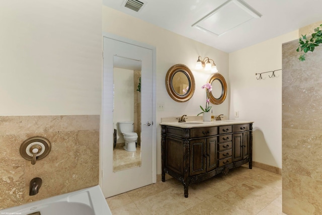 bathroom with tile patterned flooring, a tub to relax in, vanity, and toilet