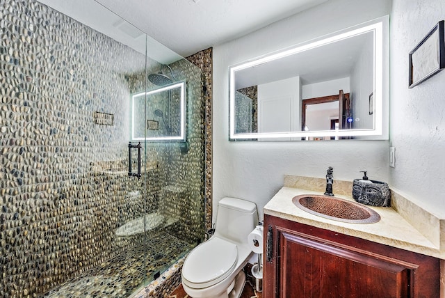 bathroom with toilet, vanity, and a shower with door