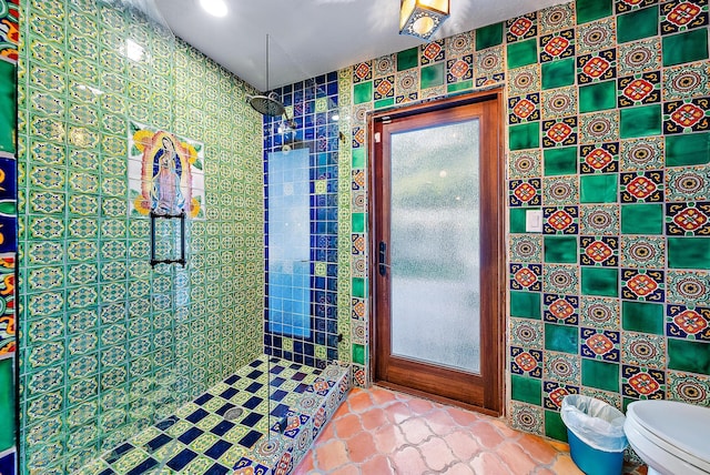 bathroom featuring tile walls, toilet, and a tile shower