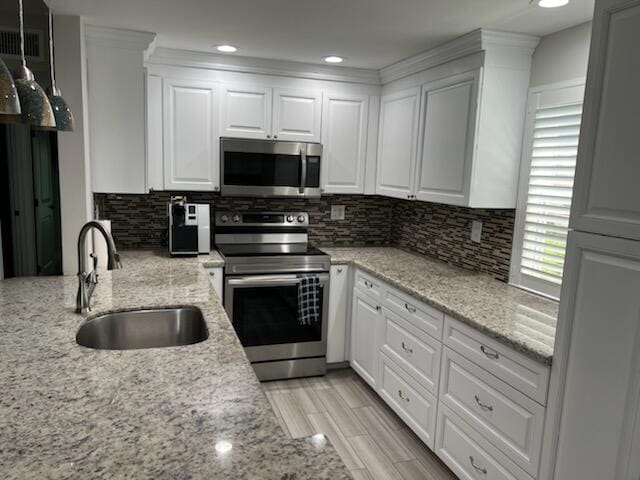 kitchen featuring white cabinets, appliances with stainless steel finishes, sink, and light stone countertops