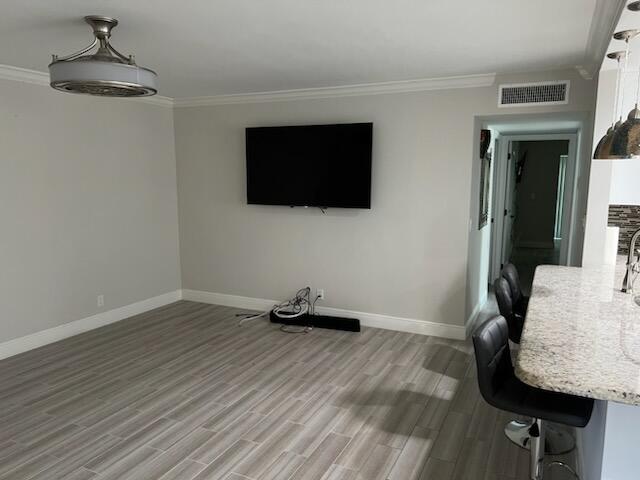 unfurnished living room with wood-type flooring and ornamental molding