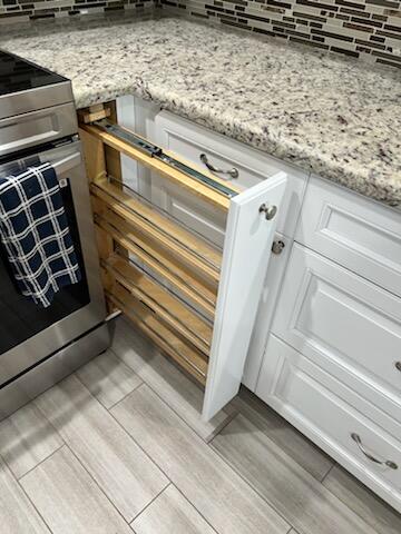 details featuring white cabinets, light hardwood / wood-style flooring, stainless steel electric range oven, and light stone countertops