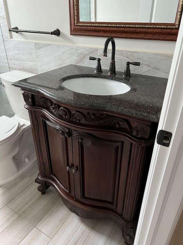 bathroom with tile walls, vanity, toilet, and wood-type flooring