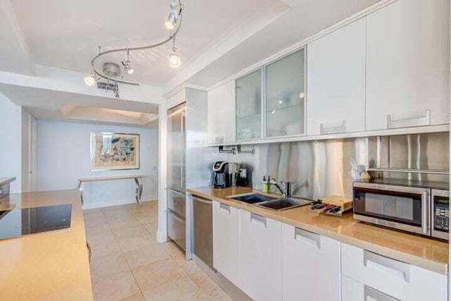 kitchen with tasteful backsplash, appliances with stainless steel finishes, sink, a raised ceiling, and white cabinetry