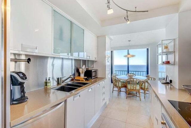 kitchen featuring sink, white cabinetry, hanging light fixtures, and a water view