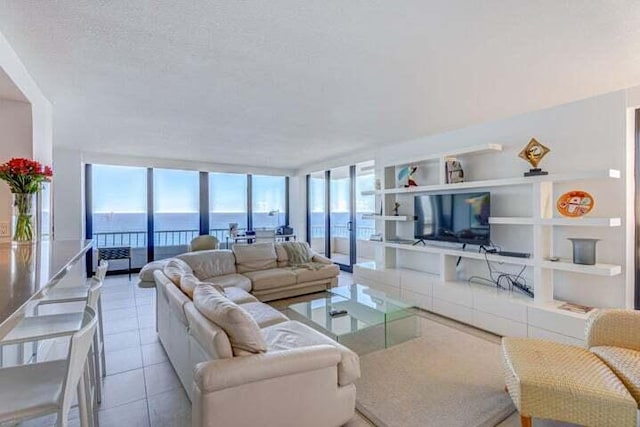 tiled living room with a textured ceiling and floor to ceiling windows