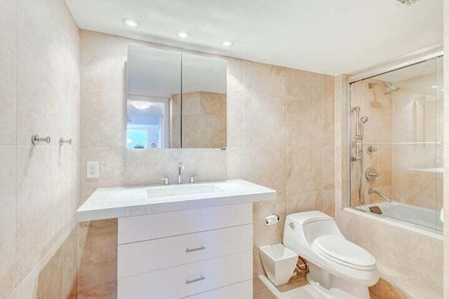 full bathroom with toilet, tile walls, tiled shower / bath, vanity, and tile patterned flooring