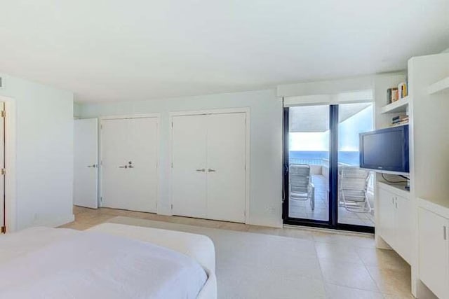 bedroom featuring multiple closets, light tile patterned flooring, and access to exterior