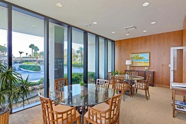 dining space featuring light carpet and a wall of windows