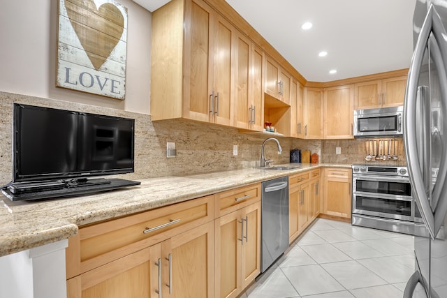 kitchen featuring light stone counters, light tile patterned floors, sink, appliances with stainless steel finishes, and decorative backsplash