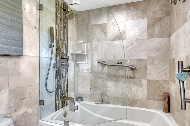 bathroom featuring tile walls, bath / shower combo with glass door, and toilet