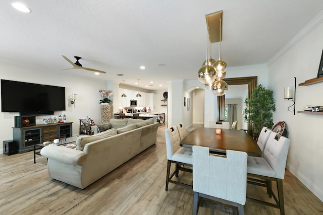 dining room with light wood-type flooring, ceiling fan, and crown molding