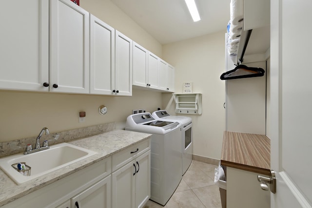 clothes washing area with washer and clothes dryer, cabinets, sink, and light tile patterned floors