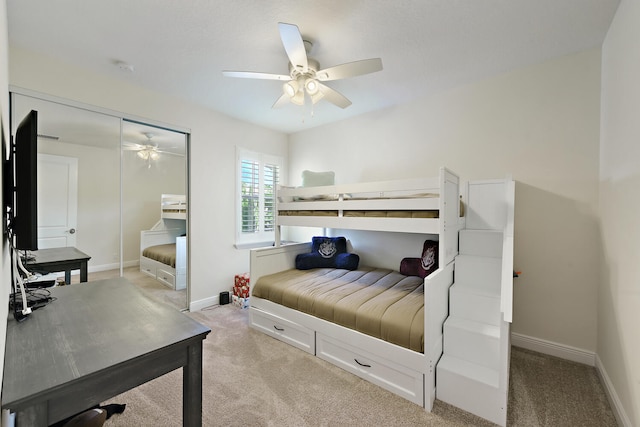 bedroom with ceiling fan, light colored carpet, and a closet