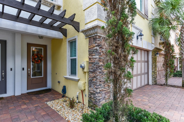 view of exterior entry with a pergola and a patio