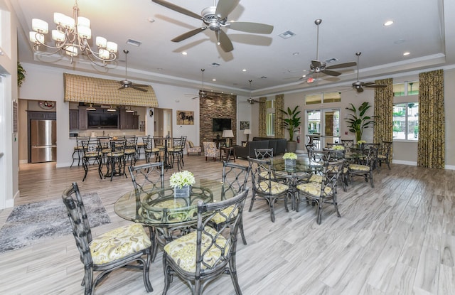 dining room with ceiling fan with notable chandelier, crown molding, and light hardwood / wood-style floors