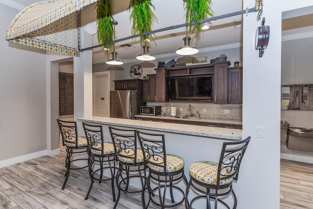 exterior space with appliances with stainless steel finishes, light wood-type flooring, dark brown cabinets, and sink