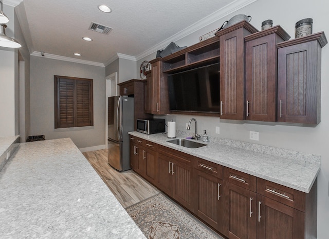 kitchen with appliances with stainless steel finishes, light hardwood / wood-style floors, a textured ceiling, ornamental molding, and sink