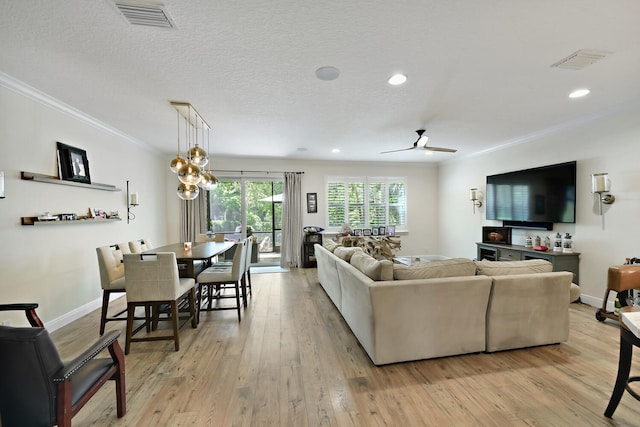 living room featuring a textured ceiling, ceiling fan with notable chandelier, light hardwood / wood-style floors, and ornamental molding