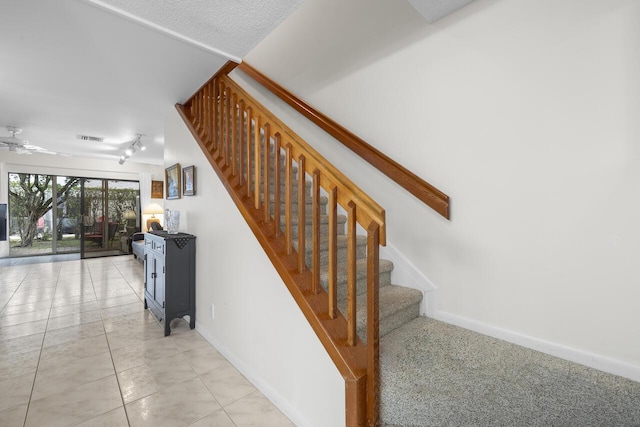 stairway featuring ceiling fan and tile patterned floors