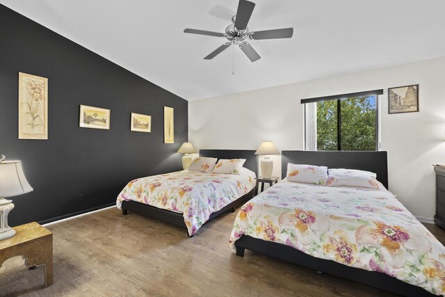 bedroom with ceiling fan, wood-type flooring, and vaulted ceiling