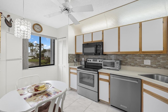 kitchen with decorative light fixtures, white cabinets, backsplash, light tile patterned floors, and stainless steel appliances