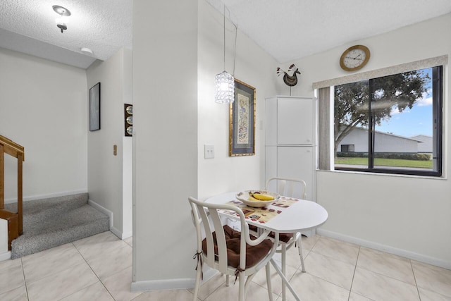 tiled dining space featuring a textured ceiling