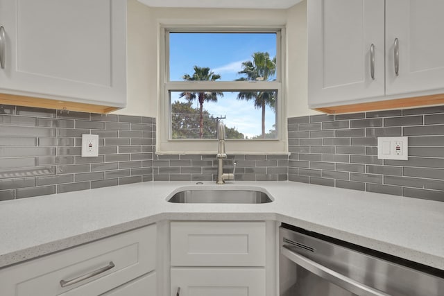 kitchen featuring dishwasher, tasteful backsplash, sink, white cabinets, and light stone countertops