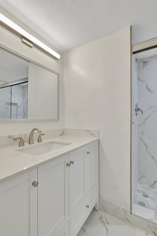 bathroom featuring vanity, a textured ceiling, and tiled shower