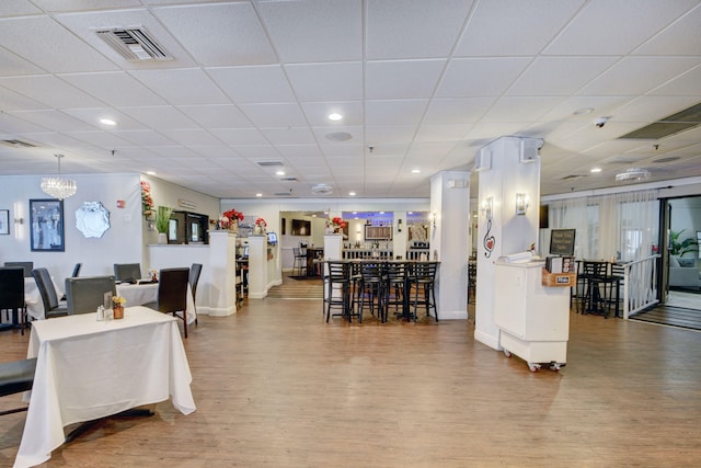 dining space with a drop ceiling and wood-type flooring