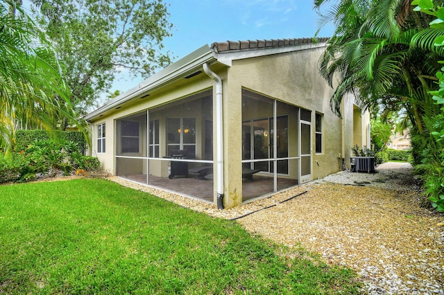 rear view of property featuring a lawn and a sunroom