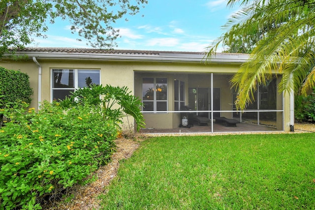 rear view of house featuring a lawn and a sunroom